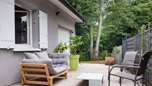 Un patio con un banco de madera, un sofá gris y una silla de metal.