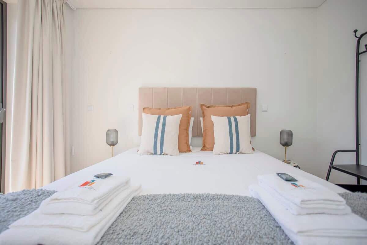A hotel room with a bed, two bedside tables, a lamp, and a window with curtains.