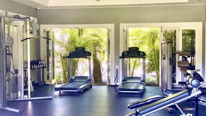 A gym with treadmills, weight machines, and a ceiling fan.