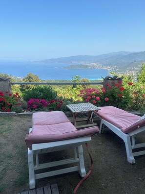 A garden with two white lounge chairs and a small table, overlooking a scenic coastal view. - Erd Villa, 5 minutes from the beach. 15–20 minutes from Ajaccio (Calcatoggio)