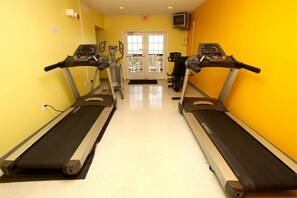 A gym with two treadmills, a door, and a television on the wall.