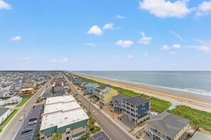 A coastal residential area with a beachfront, houses, and a road.