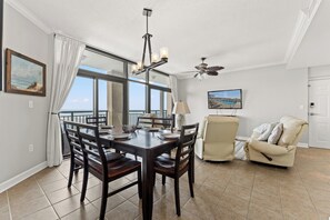 A dining area with a view of the ocean, a ceiling fan, and a television mounted on the wall. - Beach Walk Villas 908 -2BR-Cherry Grove-I/O Pools (North Myrtle Beach)