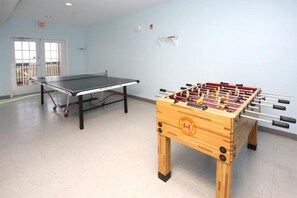 A room with a ping pong table and a foosball table.