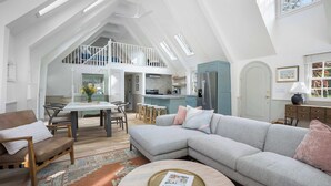 A spacious loft with a dining area, kitchen, and a large gray sectional sofa. - 1min to Private Beach, High-end Design & Hot tub (New Buffalo)