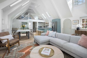 Ein großzügiges Loft mit Essbereich, Küche und einem großen, grauen Ecksofa.