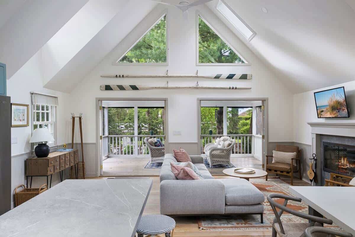 A spacious room with a high ceiling, large windows, a fireplace, and a balcony.