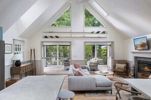 Een ruime kamer met een hoge plafond, grote ramen, een open haard en een balkon.