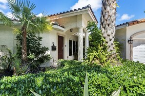 A house with a tiled roof, a palm tree, and a well-maintained garden.