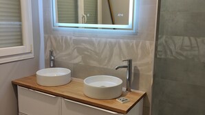 Ein modernes Badezimmer mit zwei Waschbecken, einem Spiegel und einer Duschkabine.