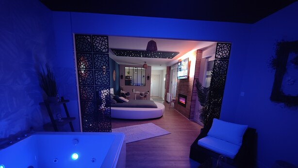 Ein modernes Wohnzimmer mit einer großen weißen Couch, einem weißen Sessel und Holzboden. Es gibt einen Kamin und ein an der Wand befestigtes Fernsehgerät.