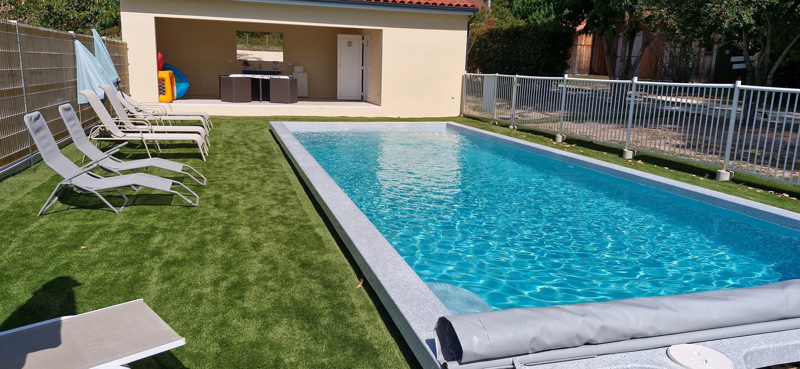 En swimmingpool med en gräsyta och solstolar.