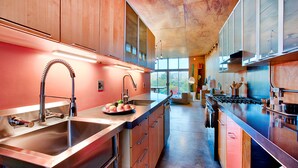 A modern kitchen with stainless steel appliances, a long countertop, and a view of the outdoors. - Creative Desert Retreat in the heart of Joshua Tree (Joshua Tree)