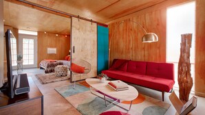 A modern living room with a red sofa, a coffee table, and a TV. - Creative Desert Retreat in the heart of Joshua Tree (Joshua Tree)