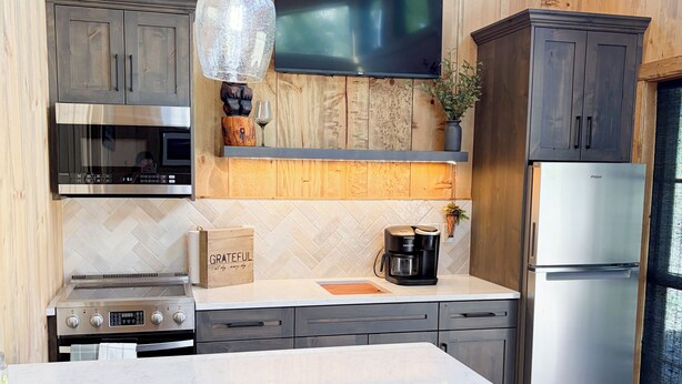 Une cuisine moderne dotée d’un grand îlot central, d’appareils électroménagers en acier inoxydable, de meubles de rangement en bois et d’une grande fenêtre.
