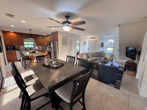 A spacious kitchen with wooden cabinets, a dining table with chairs, a ceiling fan, and a kitchen island with stools.