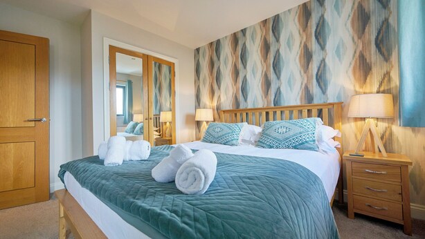 Une chambre d’hôtel avec un grand lit, deux tables de chevet, une armoire en bois et un mur décoré de motifs.
