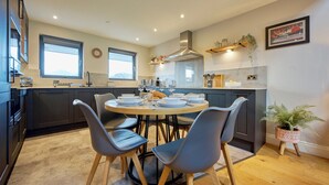 Une cuisine moderne avec une table à manger ronde, des meubles de rangement aux couleurs sombres et une grande fenêtre.