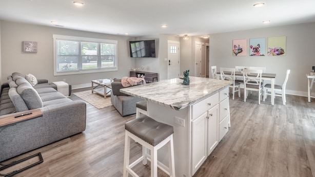 A modern kitchen with white cabinetry, a marble countertop, and a central island. - Spacious w/ all King Beds, 15 min from Beach + Downtown, Pup Friendly! (Wilmington)