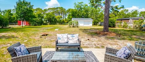 An outdoor patio area with wicker furniture, a patterned rug, and a view of a residential neighborhood.