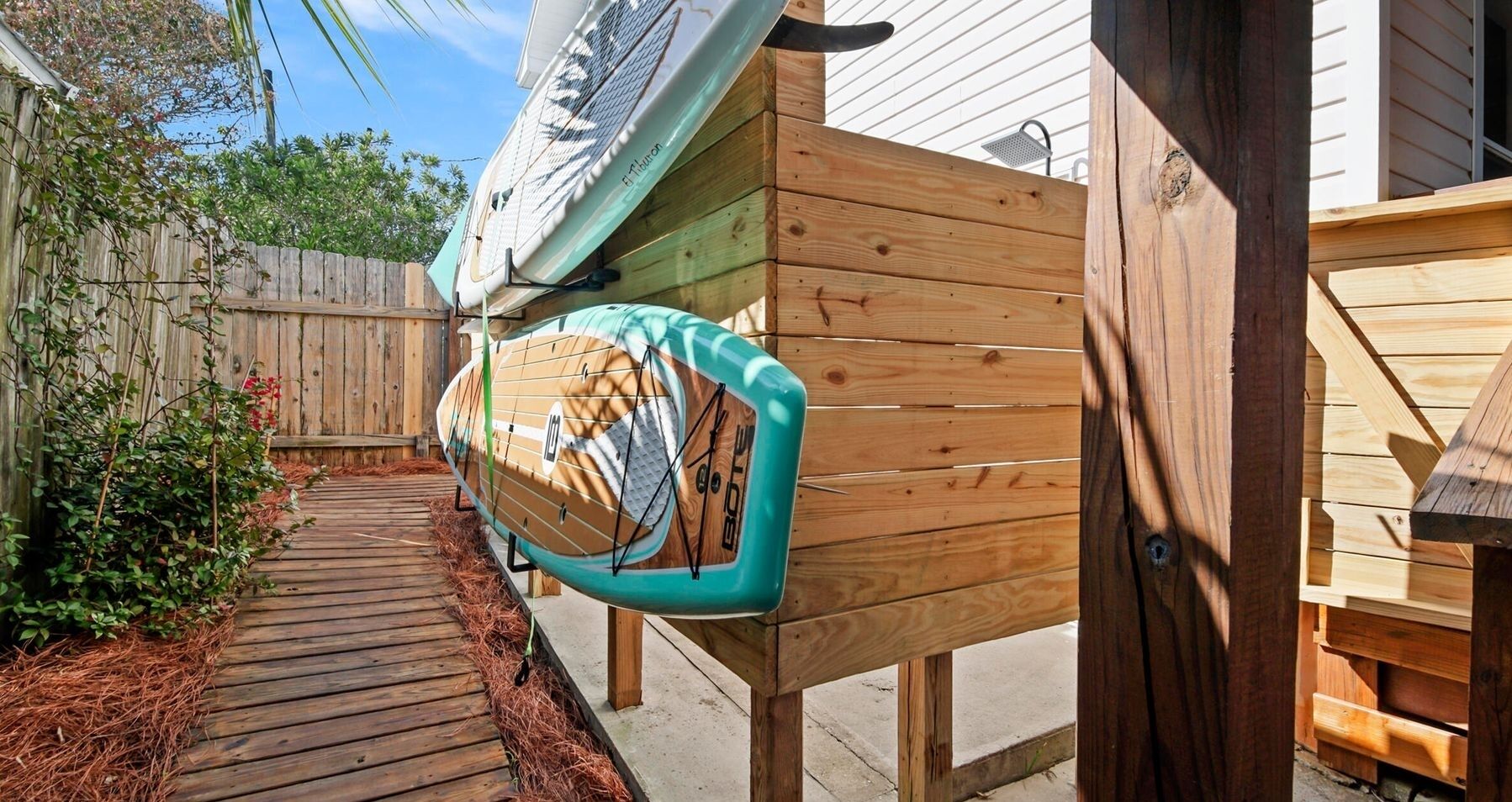 Una terraza de madera con una tabla de surf apoyada contra una estructura de madera.