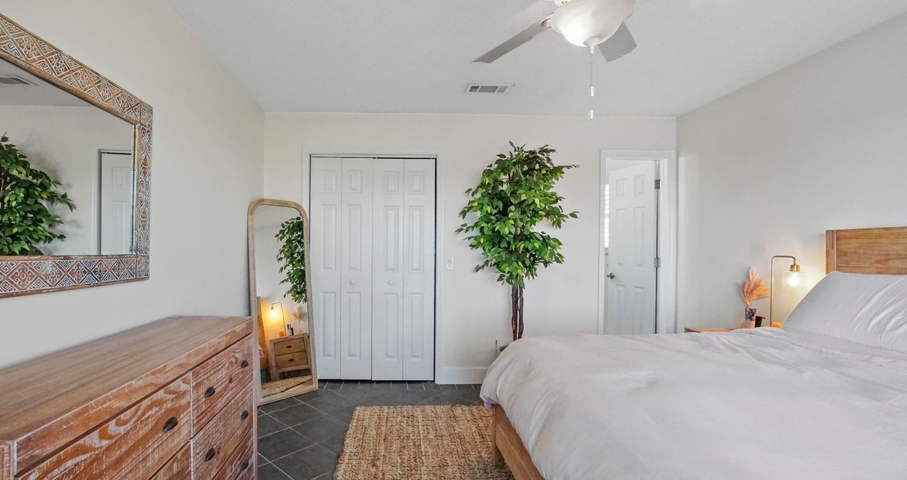 Une chambre à coucher avec un lit, une commode, un miroir et deux portes.