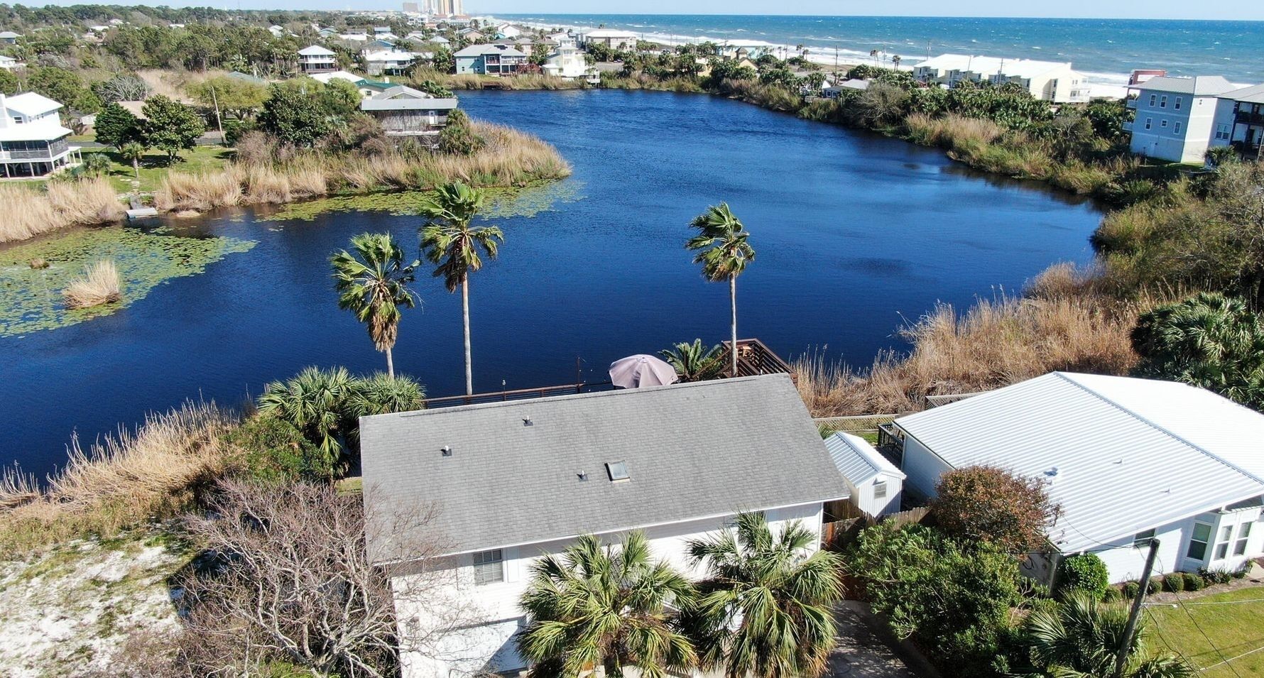 A residential area with a river, houses, and palm trees.