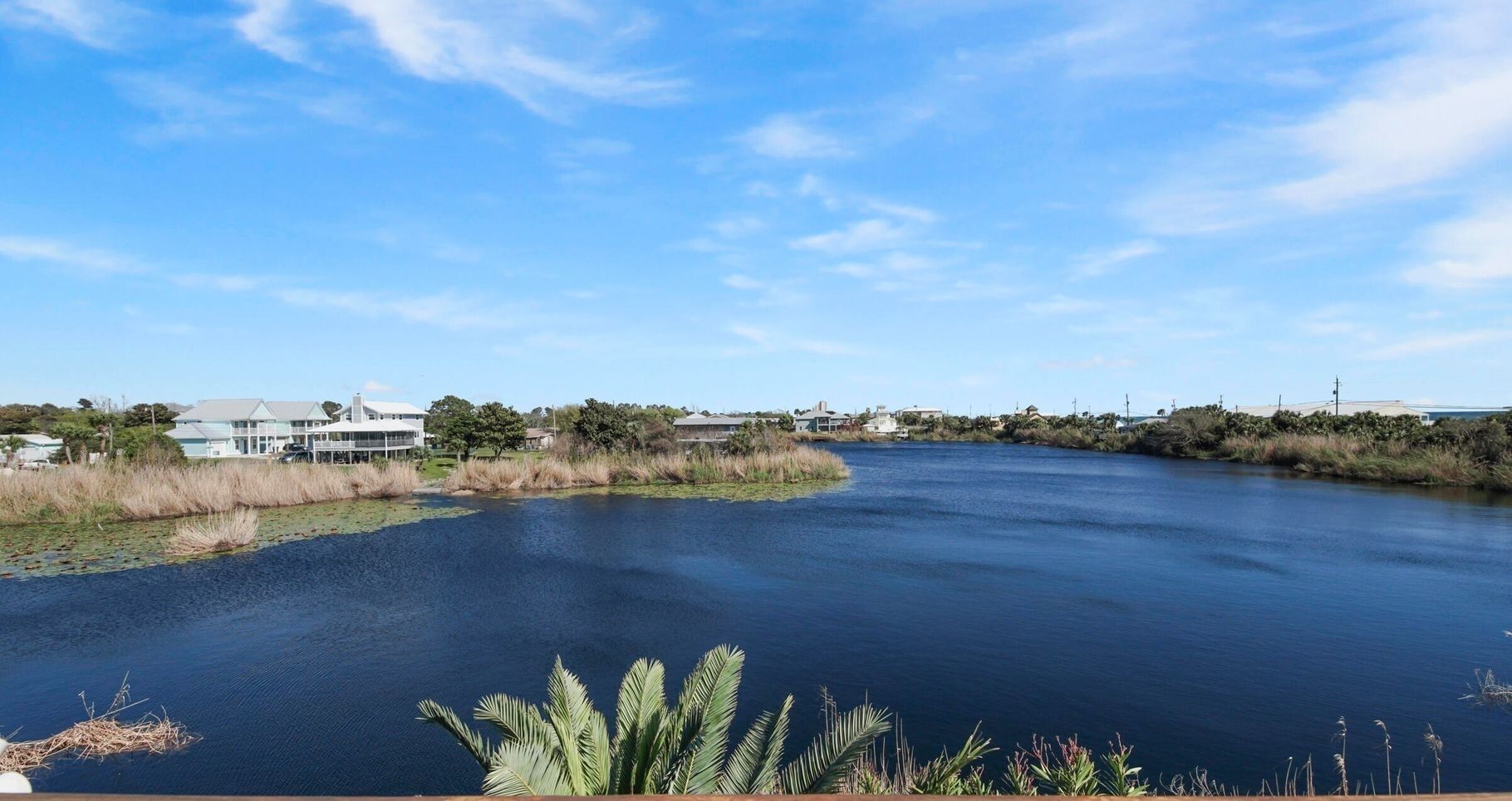 A river with a bridge, surrounded by greenery and buildings.