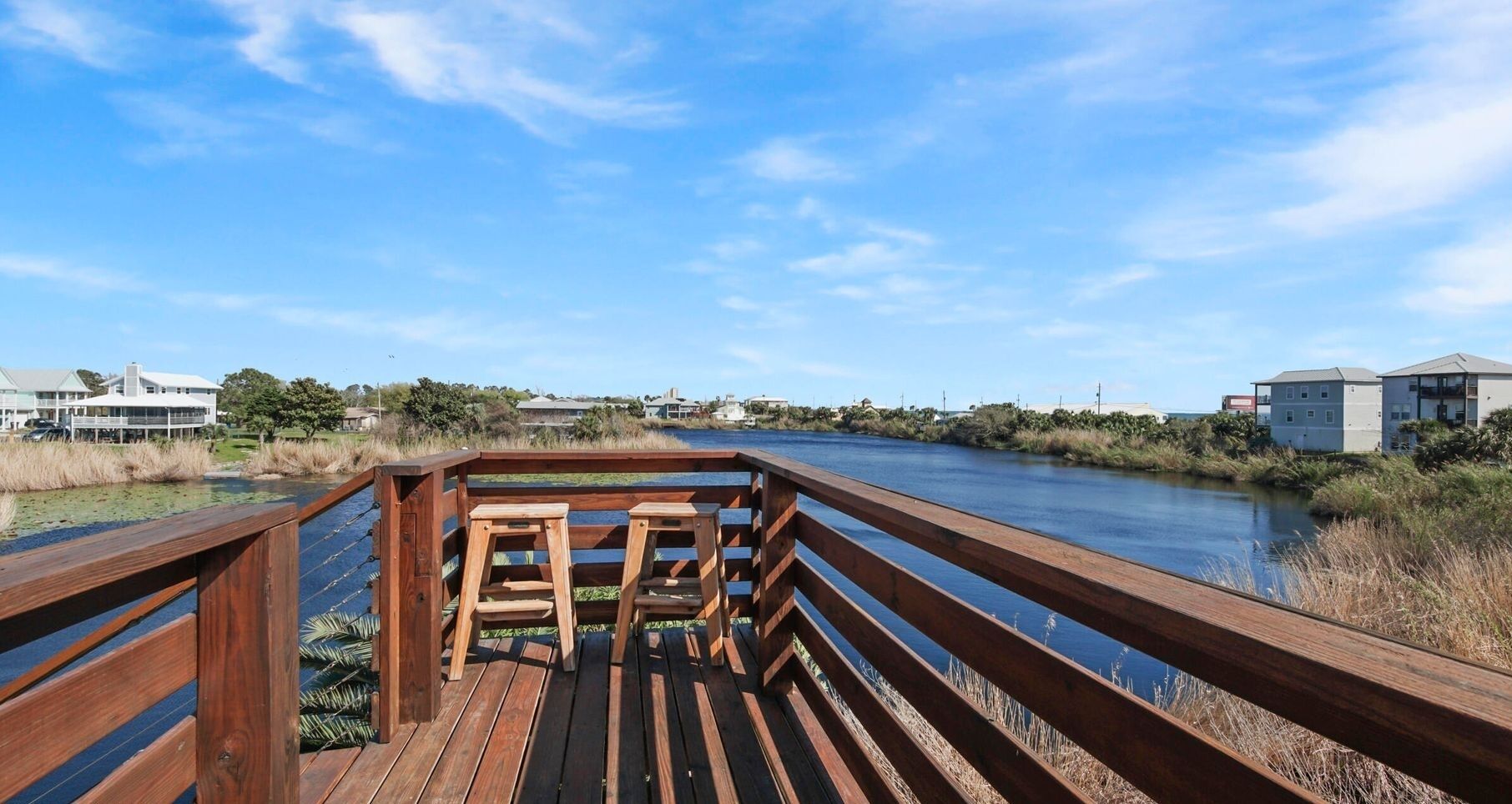 Eine Holzterrasse mit Blick auf einen Fluss und Gebäude im Hintergrund.