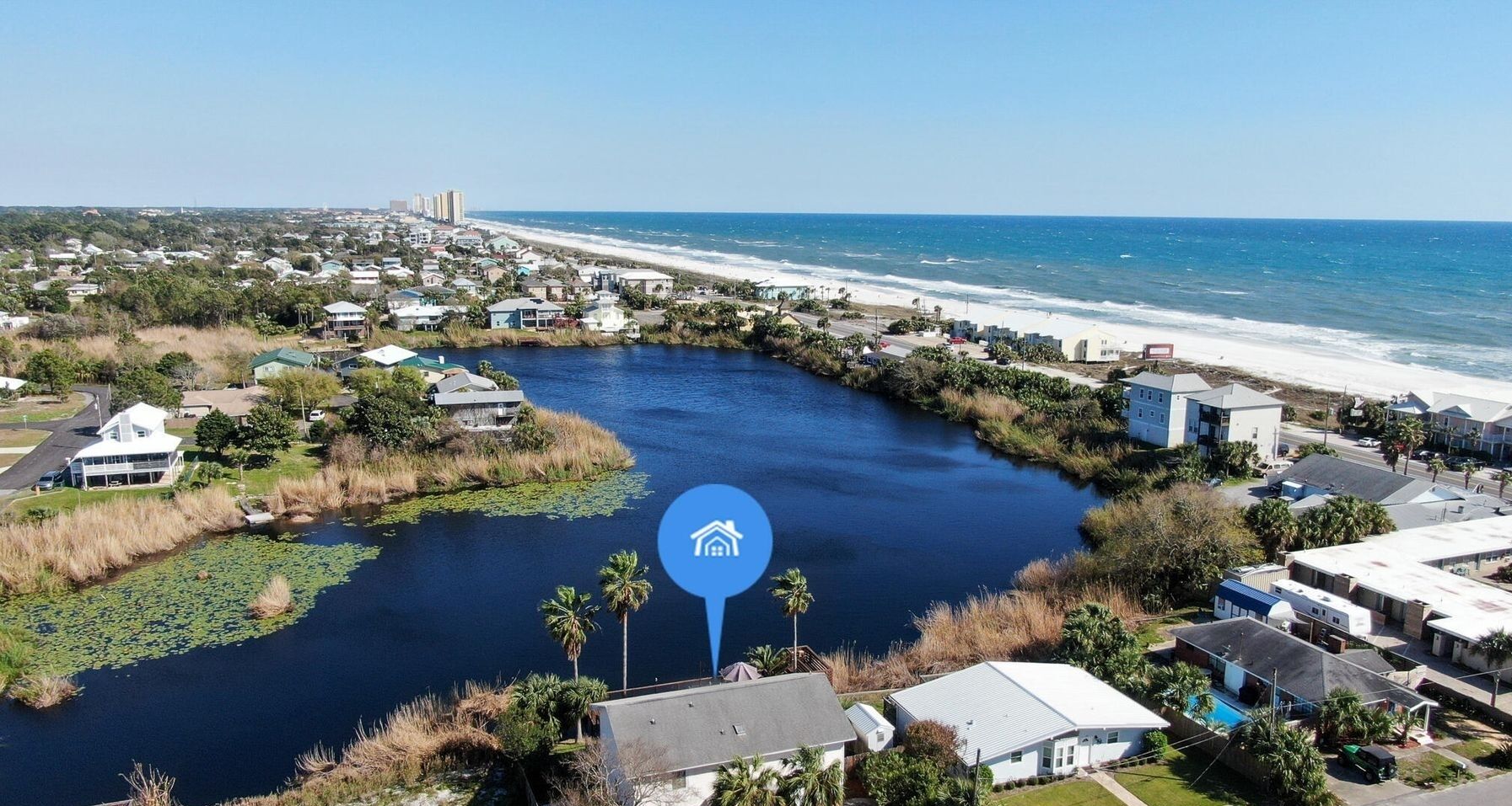 Vue aérienne d’une zone résidentielle côtière, avec des maisons, une rivière et une plage.