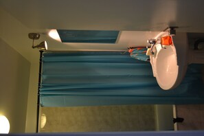 Een bad/douchecombinatie, een haardroger, handdoeken, zeep