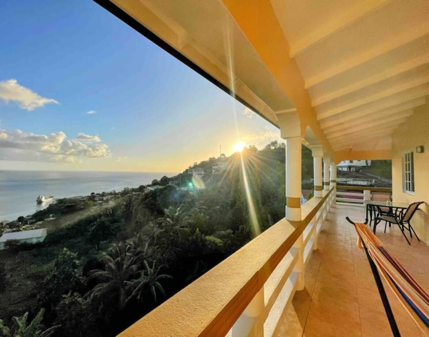 A balcony with a view of the sea and a sunset.