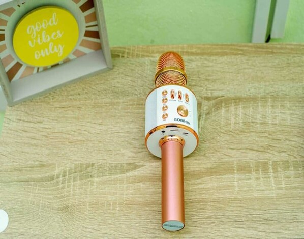 A microphone with a white and gold design, placed on a wooden surface.