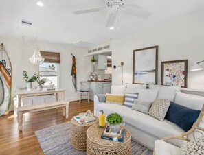 A spacious living room with a white sofa, a wooden coffee table, and a ceiling fan.