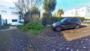 A paved driveway with a parked SUV, surrounded by greenery and modern buildings. - APARTMENT FACING FONCILLON BEACH (Royan)
