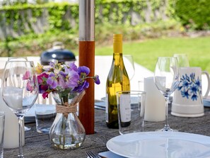 Une table mise pour un repas, avec un vase de fleurs, des bouteilles de vin et de la verrerie.