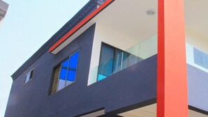 Un bâtiment moderne doté d’un toit plat, de grandes fenêtres et d’un élément décoratif rouge sur l’angle.