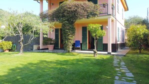 Une maison à deux étages avec un balcon, un petit jardin et un chemin pavé.