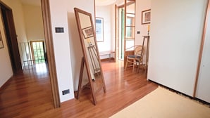 Un couloir doté d’un plancher en bois, d’un chevalet, d’une chaise et d’une porte donnant sur une autre pièce.