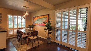 A dining area with a table, chairs, a painting, and a potted plant. - Well Appointed fully furnished 2BR, 2Bath, 1st floor, Guard-Gated, Biltmore area (Phoenix)