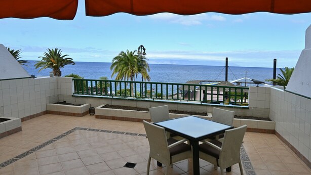A balcony with a view of the ocean, a table with chairs, and a railing. - 1st Line Sea View · Plaza Terrace (Santiago del Teide)