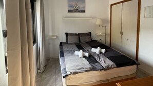 A bedroom with a bed, a ceiling fan, a painting, a wardrobe, and a bedside table. - 1st Line Sea View · Plaza Terrace (Santiago del Teide)