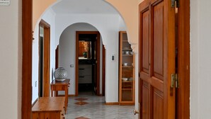 A hallway with a wooden bench, a tiled floor, and an arched doorway leading to a kitchen area. - 1st Line Sea View · Plaza Terrace (Santiago del Teide)