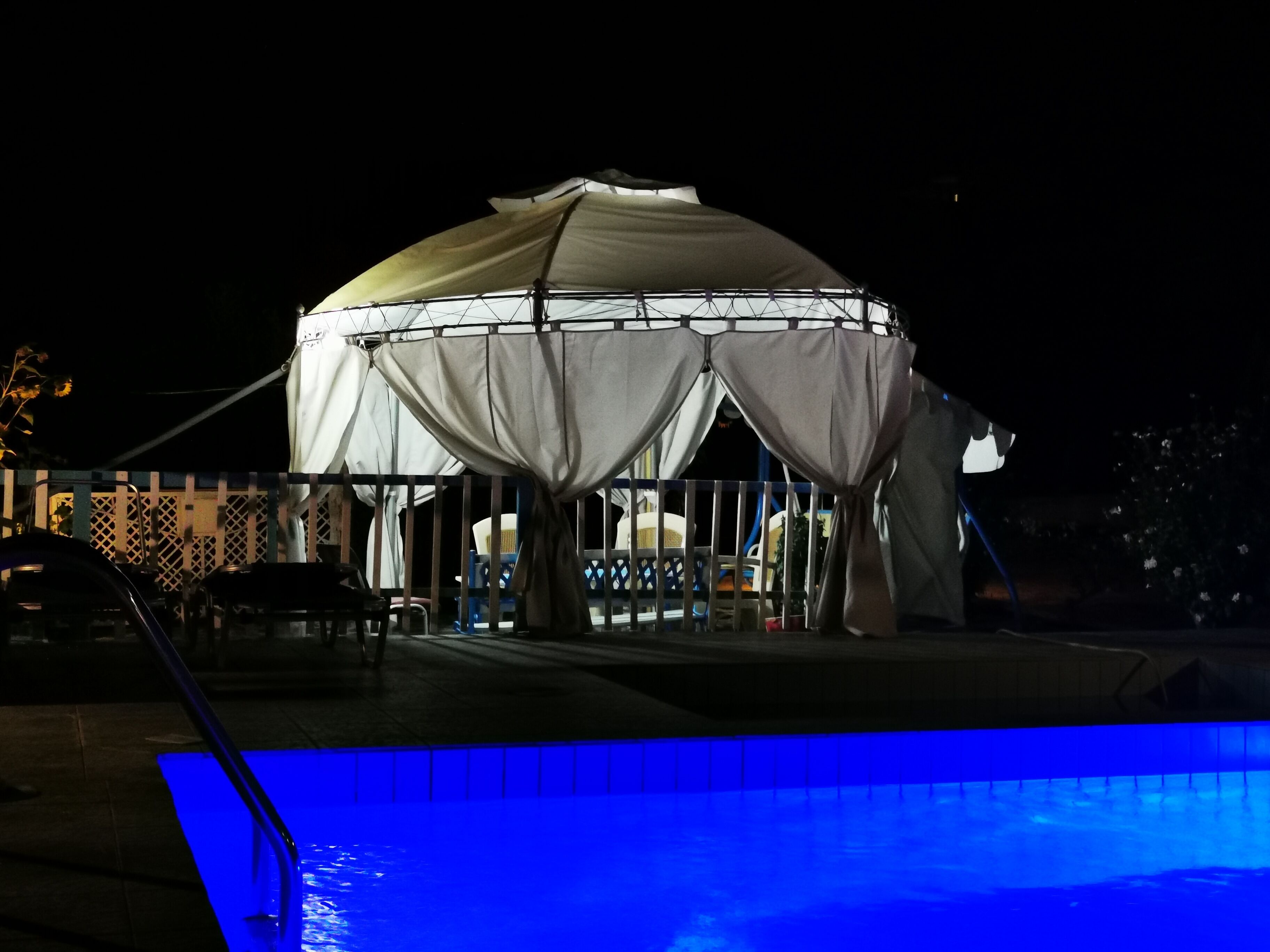 Un espace extérieur abrité, doté d’une piscine, qui pourrait être un salon ou un bar situé au bord de la piscine.
