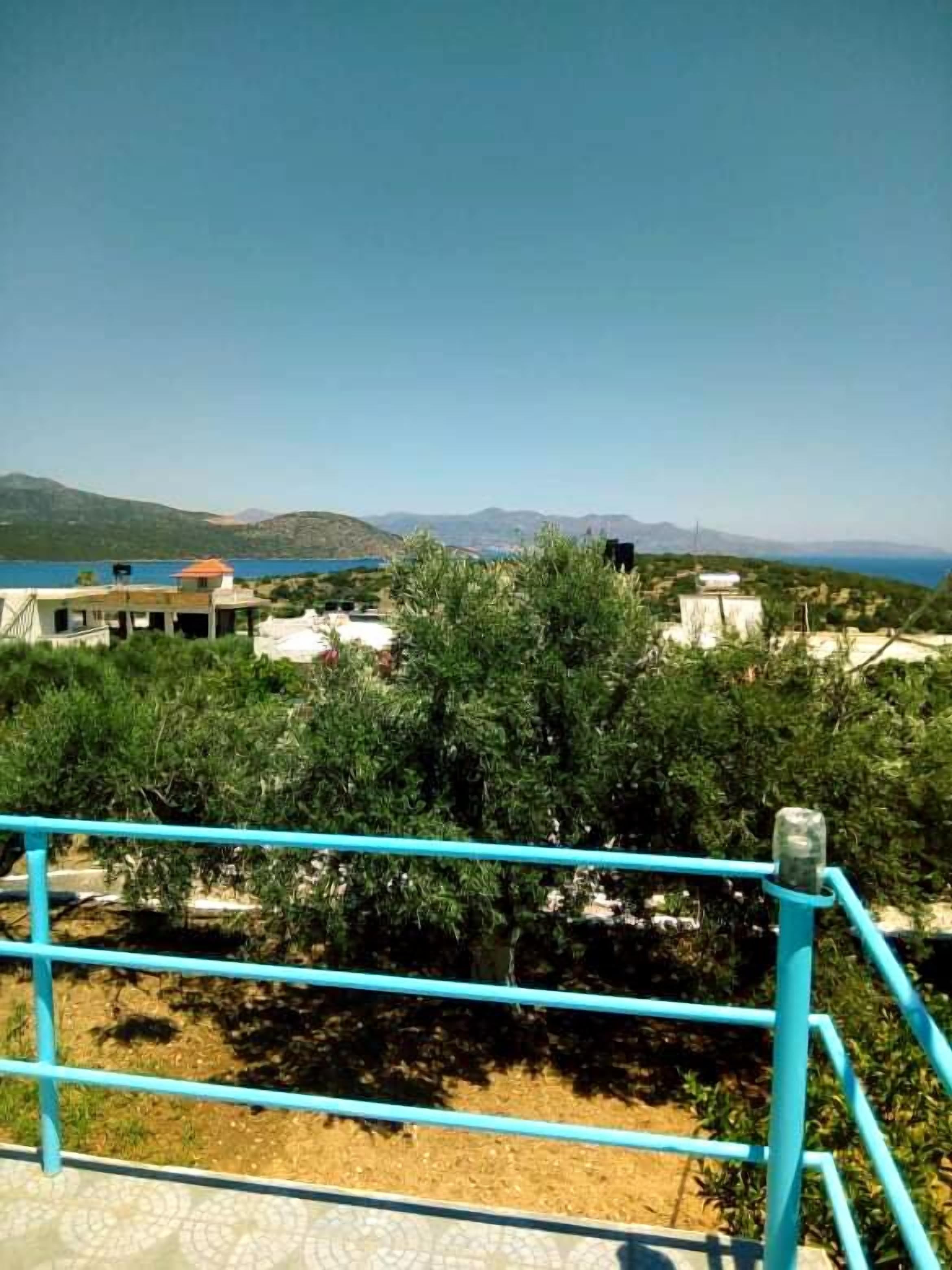 A terrace with a view of a coastal landscape, including buildings and hills.