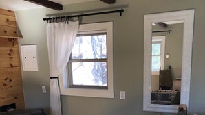 A cozy living room with a sofa, a bench, a fireplace, and a window with curtains.