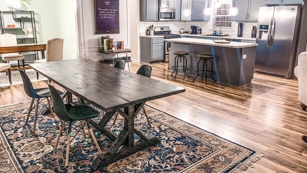 Cozinha moderna com armários cinzas, eletrodomésticos de aço inoxidável e uma ilha central com banquetas.