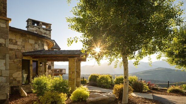A stone building with a curved roof, a stone chimney, and a view of mountains in the background. - Outpost: Teton Retreat - Expansive Teton Views (Jackson)