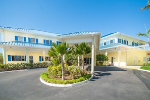 A hotel with a covered entrance, palm trees, and a clear blue sky. - Castaways Cove Unit 122  Beach Front direct access (East End)