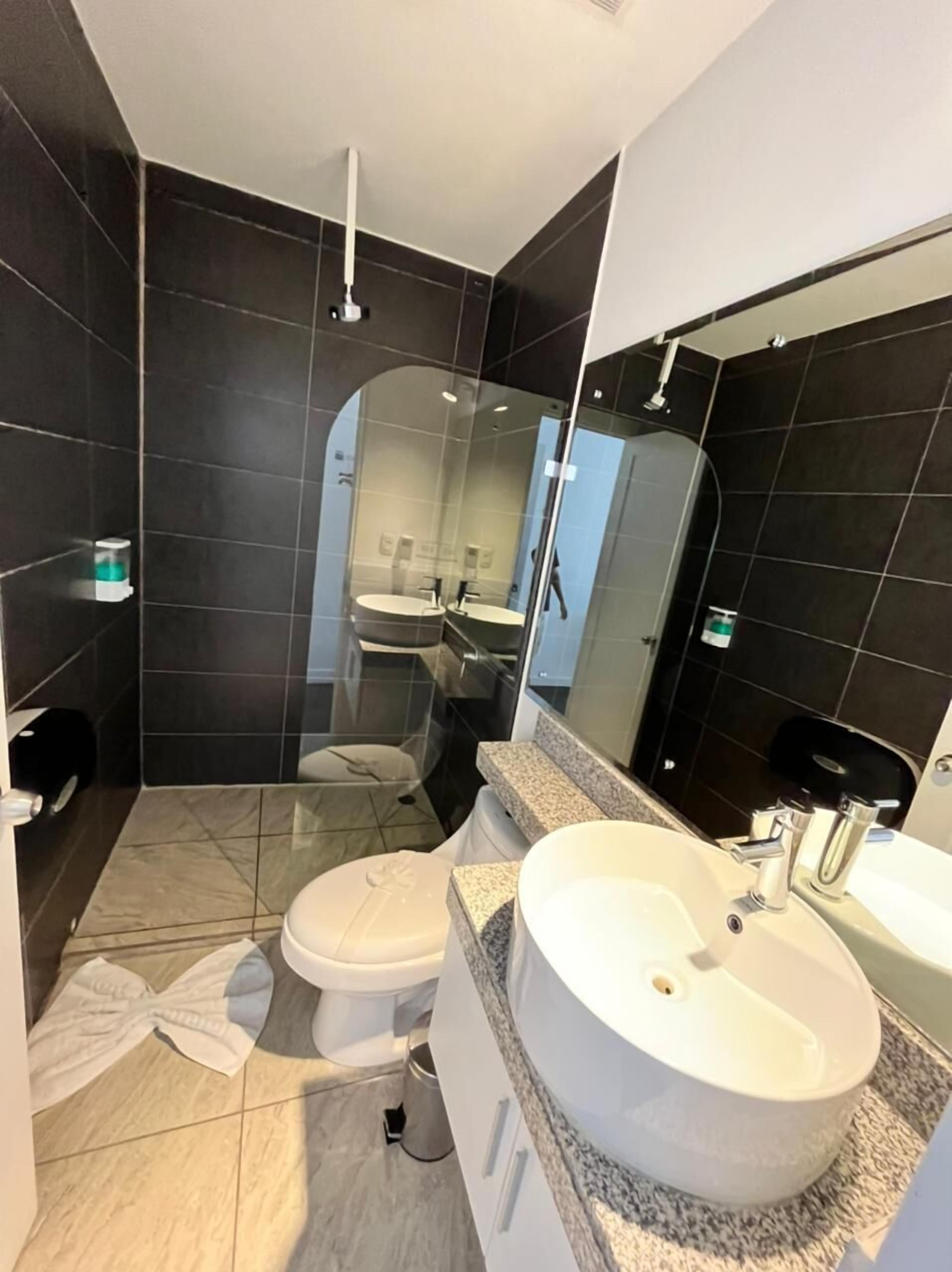 Een moderne badkamer met een douchecabine van glas, een wit toilet en een ruime wastafel met een granieten blad.